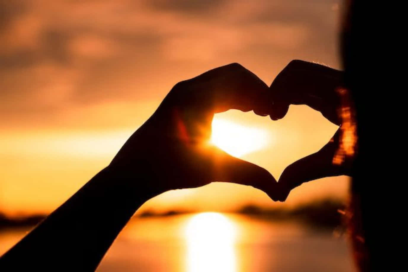 Heart Silhouette 桌布 壁紙 — 剪影雙手形成心形，框住水面上閃耀的日落。