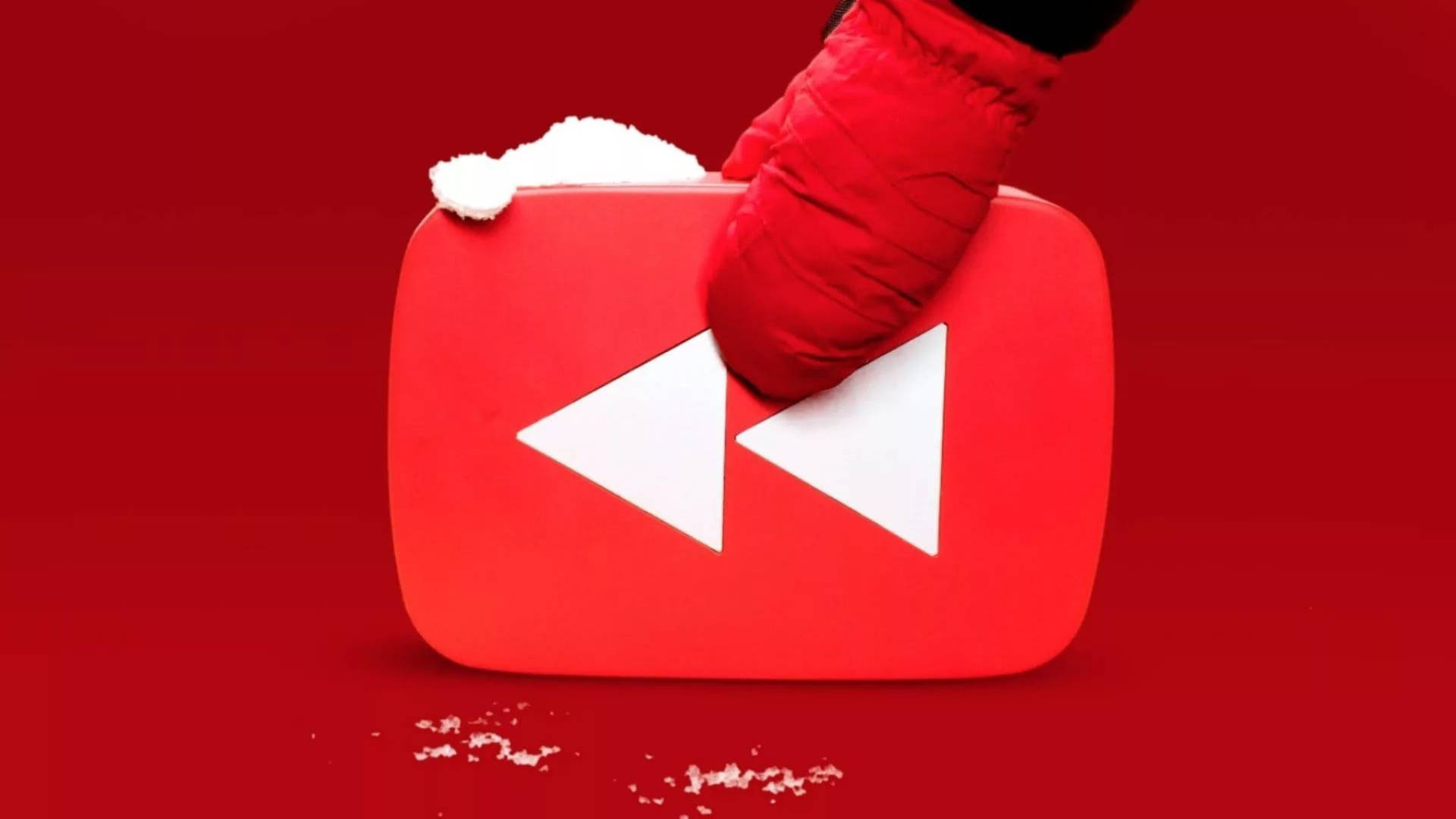 戴紅色手套的手拿著一個被雪覆蓋的YouTube播放按鈕。