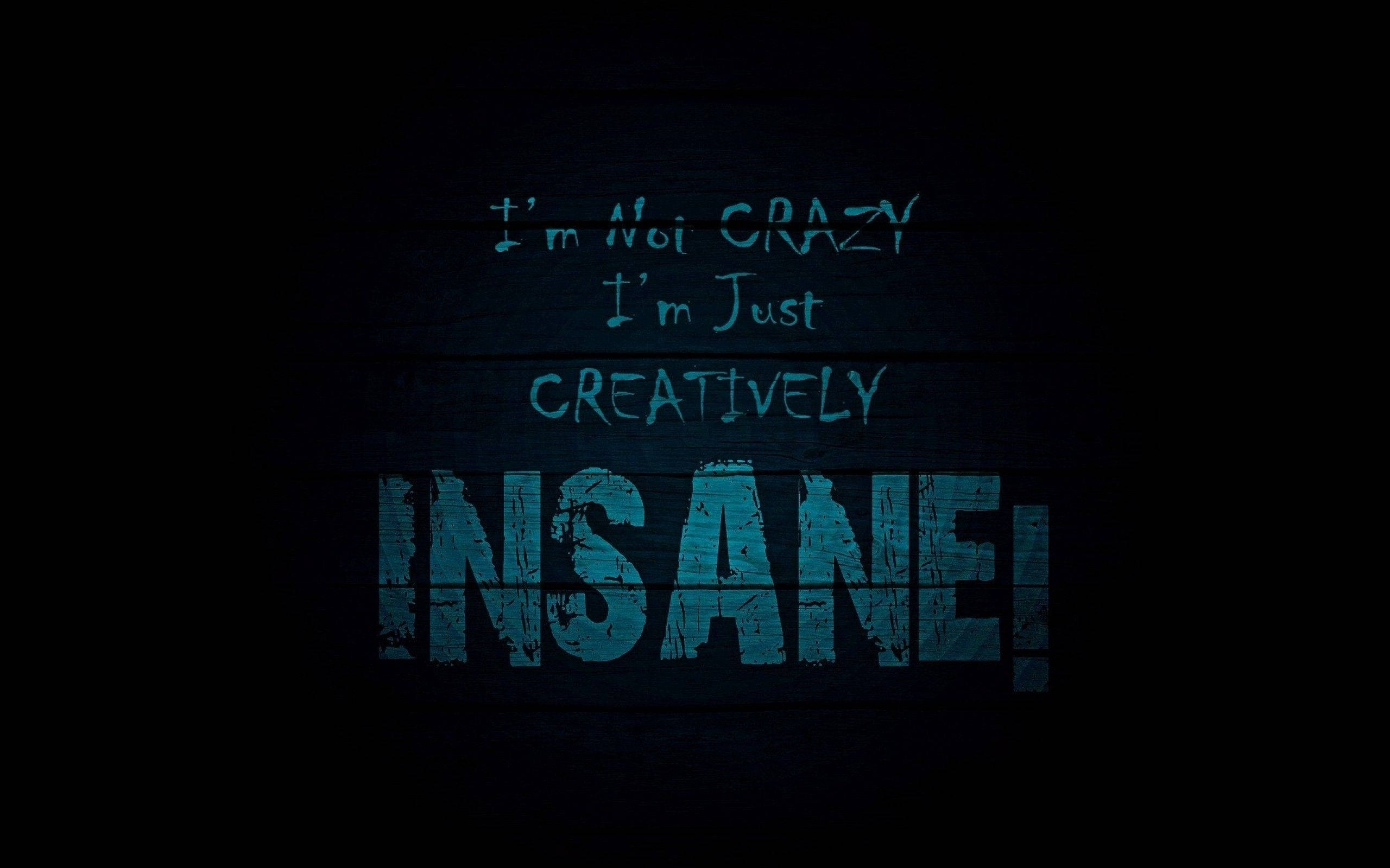 創意瘋狂暗色語錄 壁紙 — 大膽的藍色文字在深色木牆上宣告「I'm Not Crazy I'm Just Creatively Insane!」。
