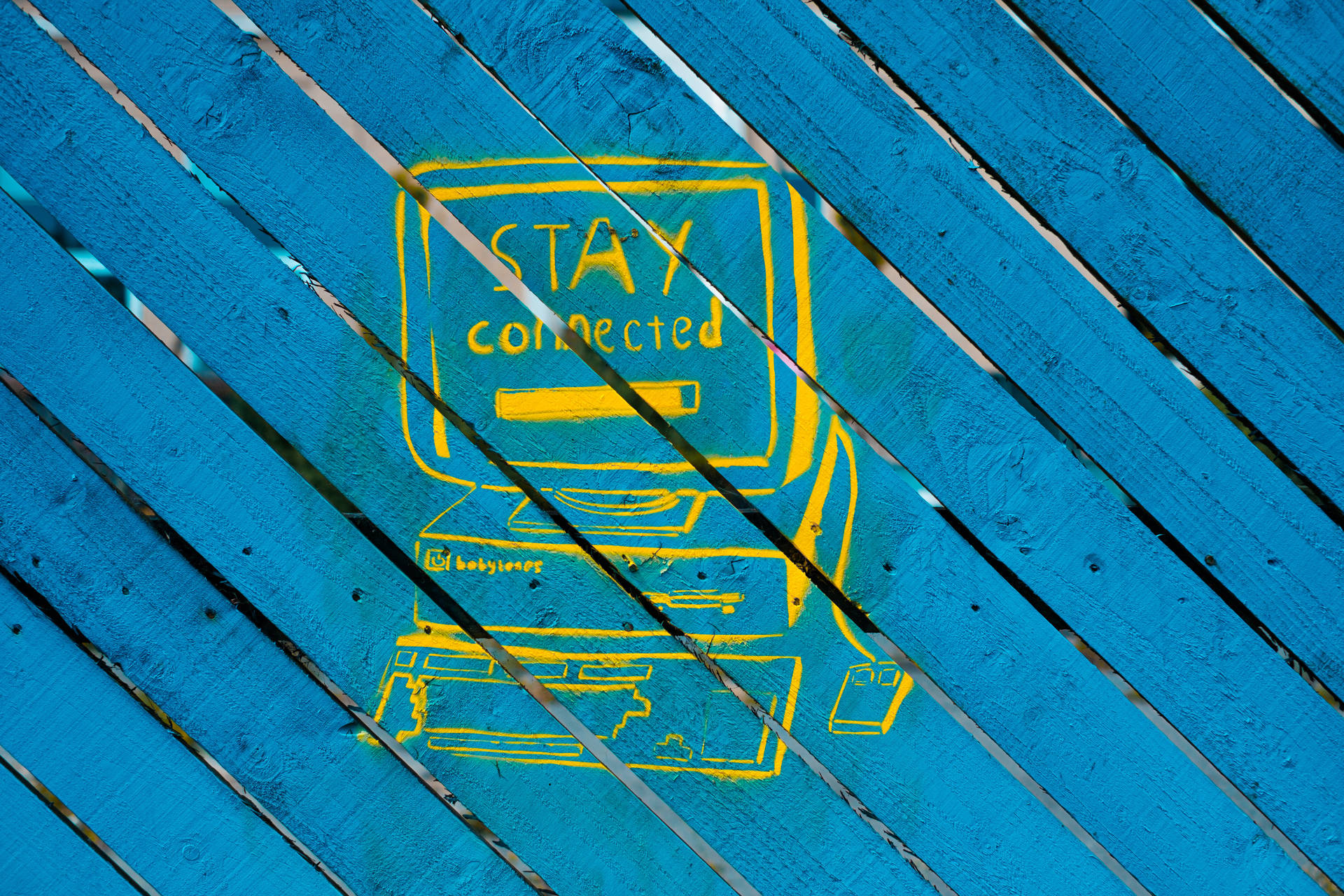 黃色塗鴉畫，畫有一部電腦，藍色木條上寫有「STAY connected」。