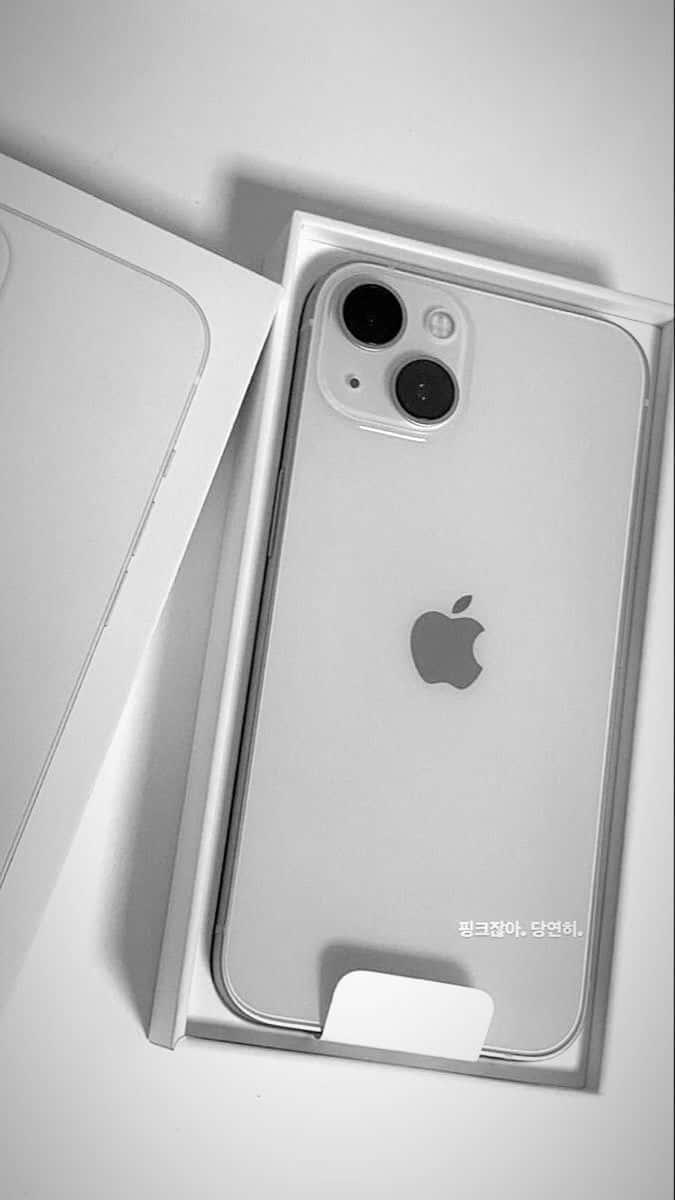 創新世代：隆重推出 iPhone 12！ 壁紙 — 一部時尚的銀色iPhone安放在打開的盒子中，極簡的單色燈光突出其相機和標誌。