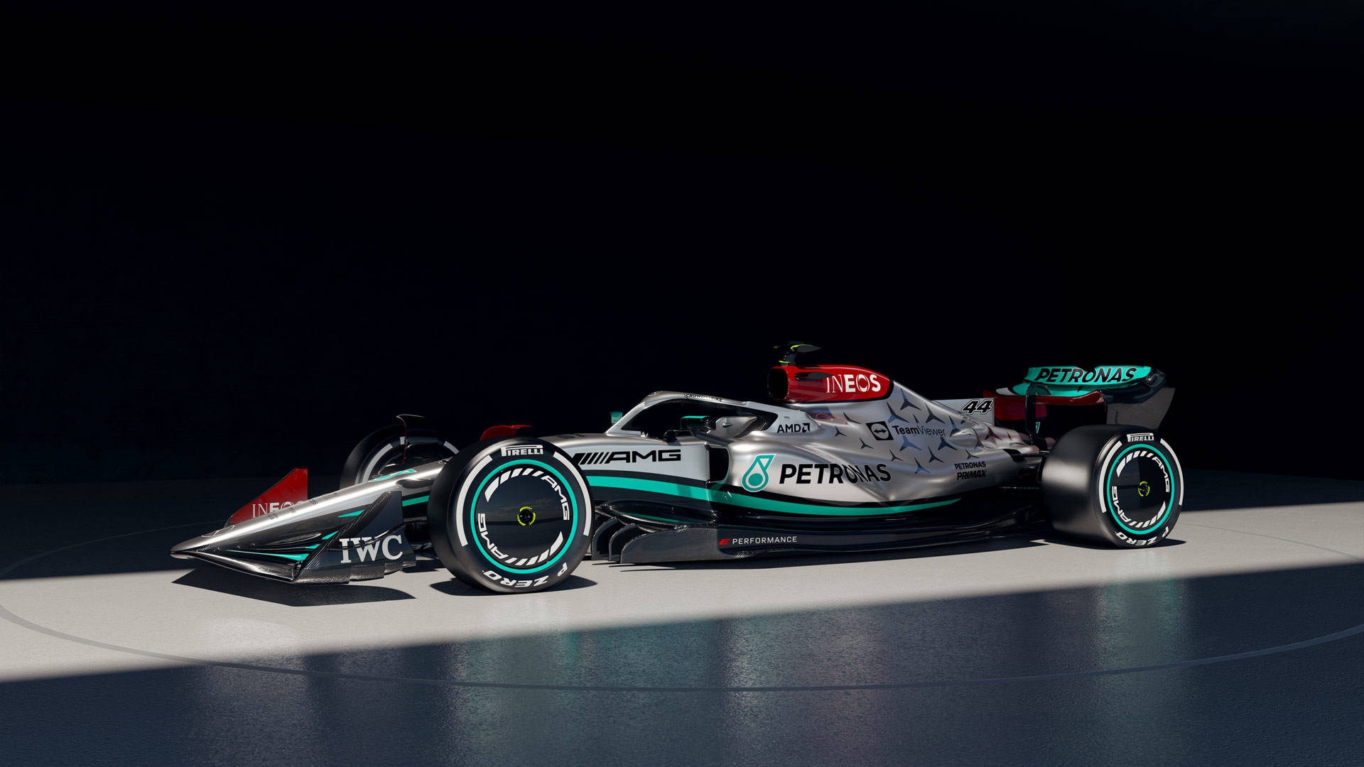 一輛帶有Petronas品牌的銀色和藍綠色一級方程式賽車，在工作室燈光下。