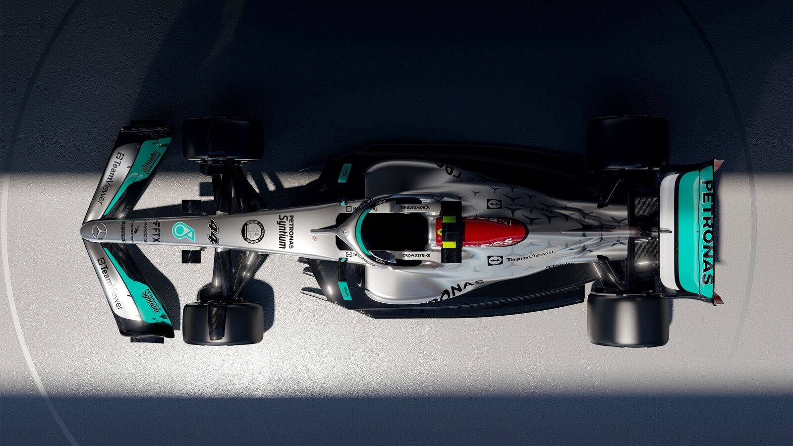 從上方俯瞰一輛帶有 Petronas 贊助的 Formula 1 賽車在混凝土表面上。