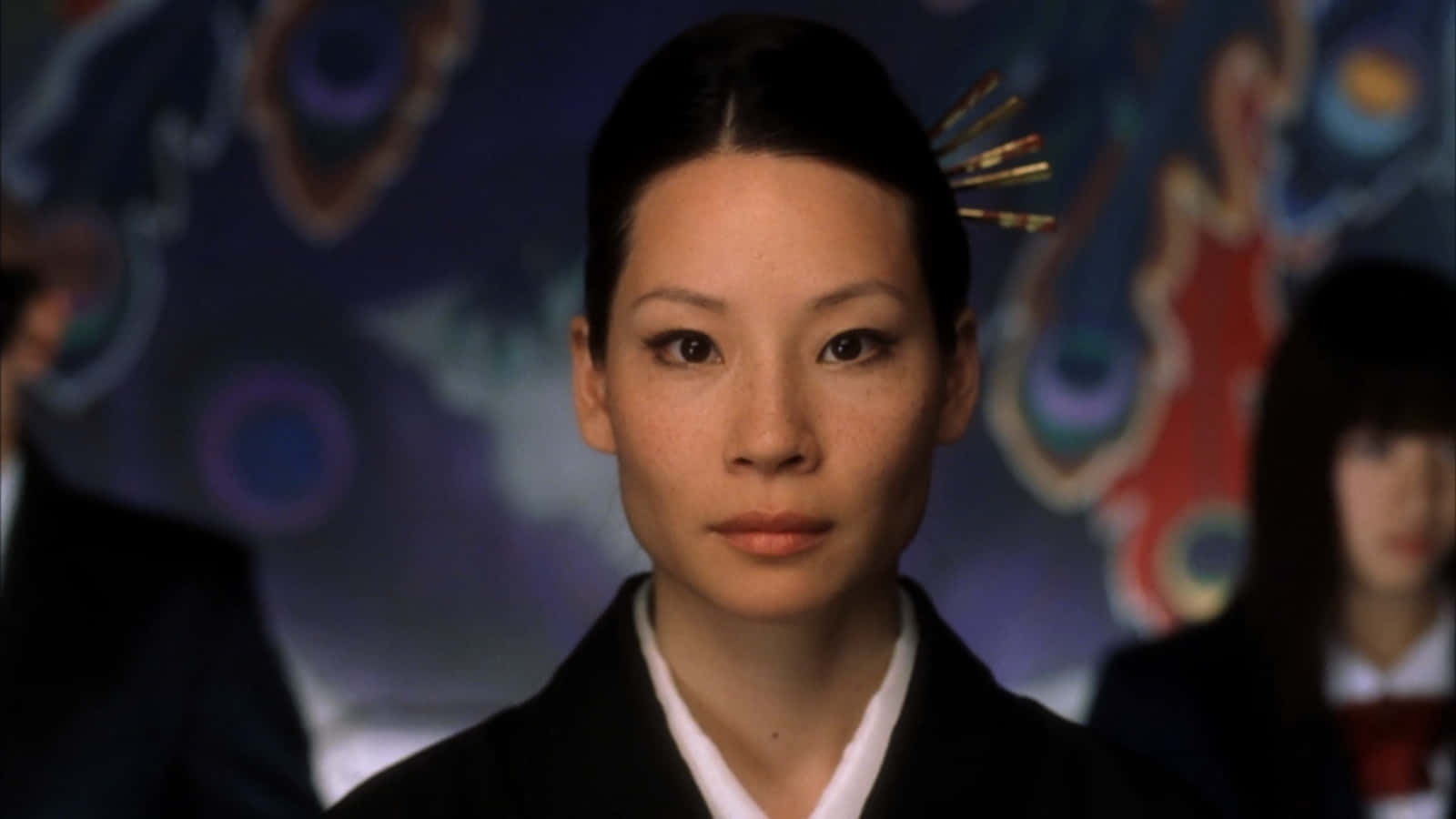 身穿傳統日本和服、頭戴髮簪的女性，映襯著色彩繽紛的抽象背景。