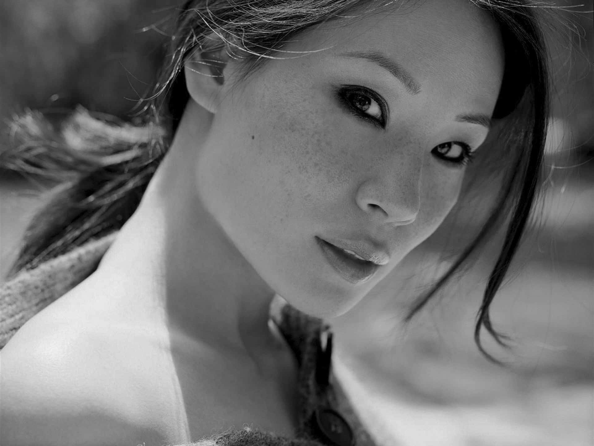 一位有雀斑的女性在黑白肖像中直視鏡頭。
