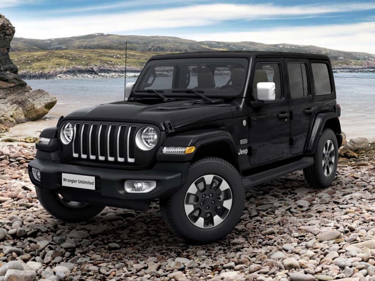 黑色Jeep Wrangler Unlimited停在水邊的岩石海灘上