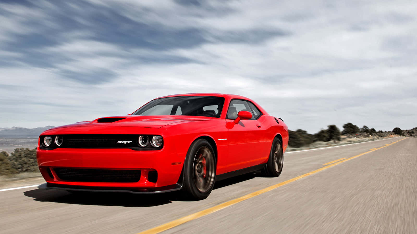 紅色道奇挑戰者SRT在背景模糊的沙漠公路上加速行駛。