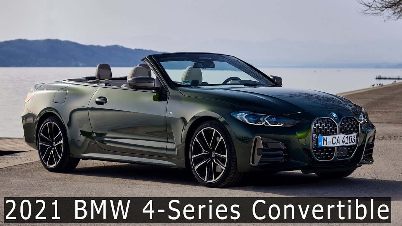 「力量與風格」 壁紙 — 一架時尚的深綠色2021年BMW 4系開篷車停在平靜的湖邊，遠處有山丘，天空朦朧。