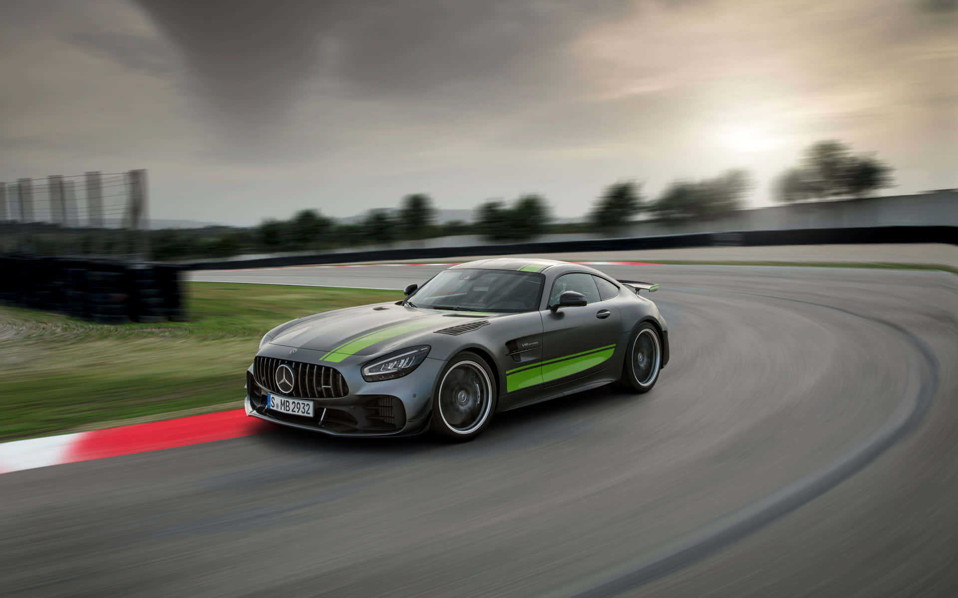 帶有綠色條紋的灰色 Mercedes-AMG GT 在日落時分的賽道上飛馳。