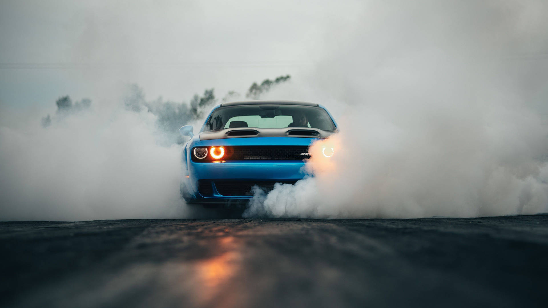 藍色肌肉車在潮濕路上燒胎，伴隨煙霧和發光車頭燈。 — Dodge challenger GIF 壁紙