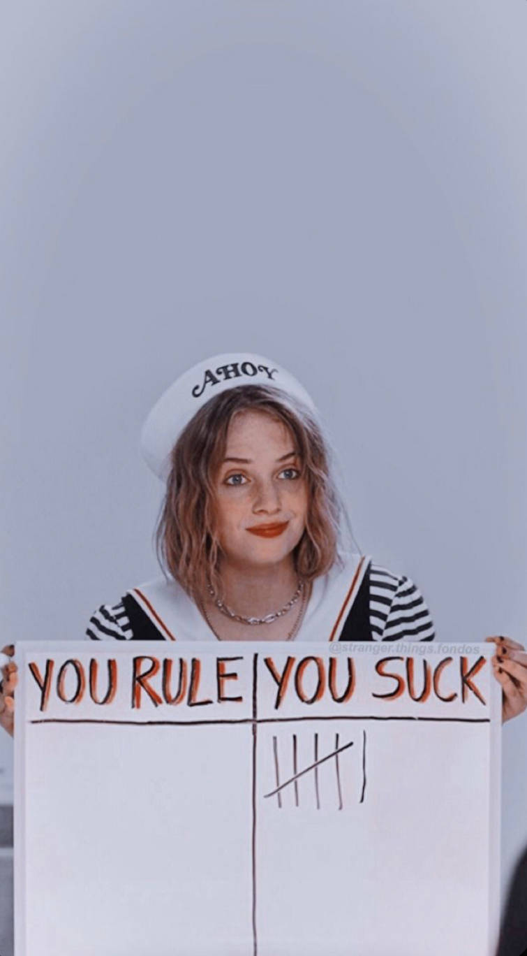 戴水手帽的年輕女子拿著一個分開的牌子，上面有「you rule」和「you suck」的正字記號。