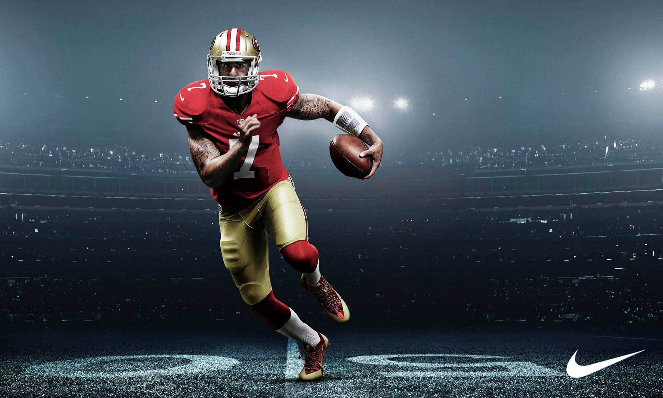 加入NFL熱潮，盡享高清影像 壁紙 — 三藩市四九人隊的四分衛身穿紅金色制服，在球場燈光下持球衝刺。