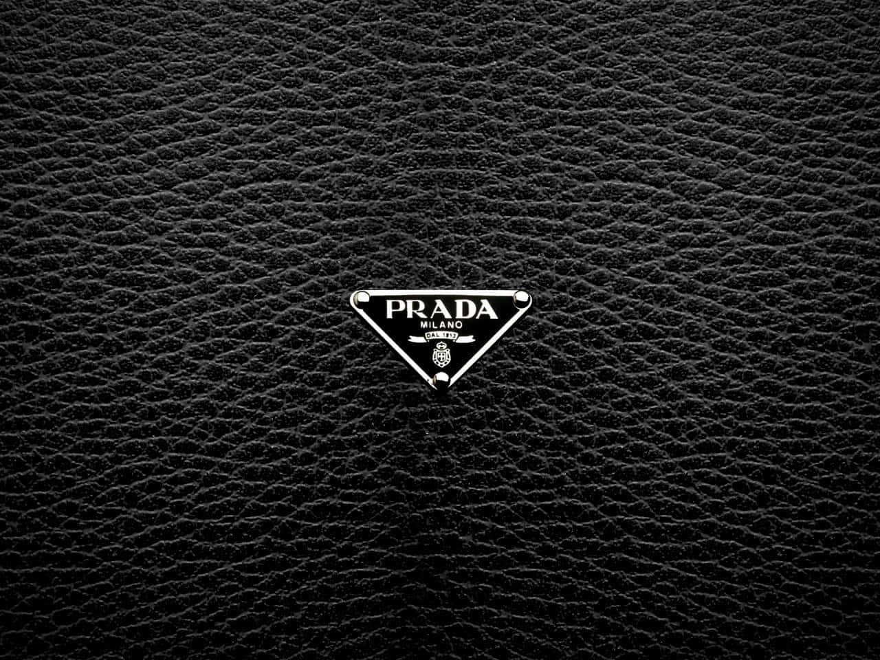 加入普拉達的生活 壁紙 — 一個時尚的Prada標誌徽章，居中於帶有金屬銀色飾邊的紋理黑色皮革上。