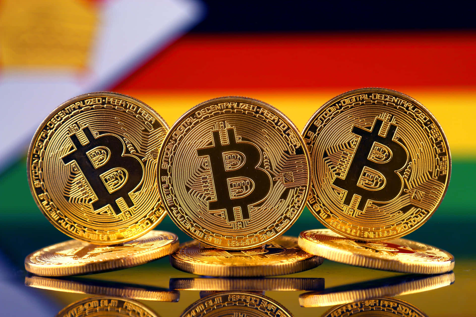 三枚金色比特幣硬幣，背景為德國國旗及倒影。