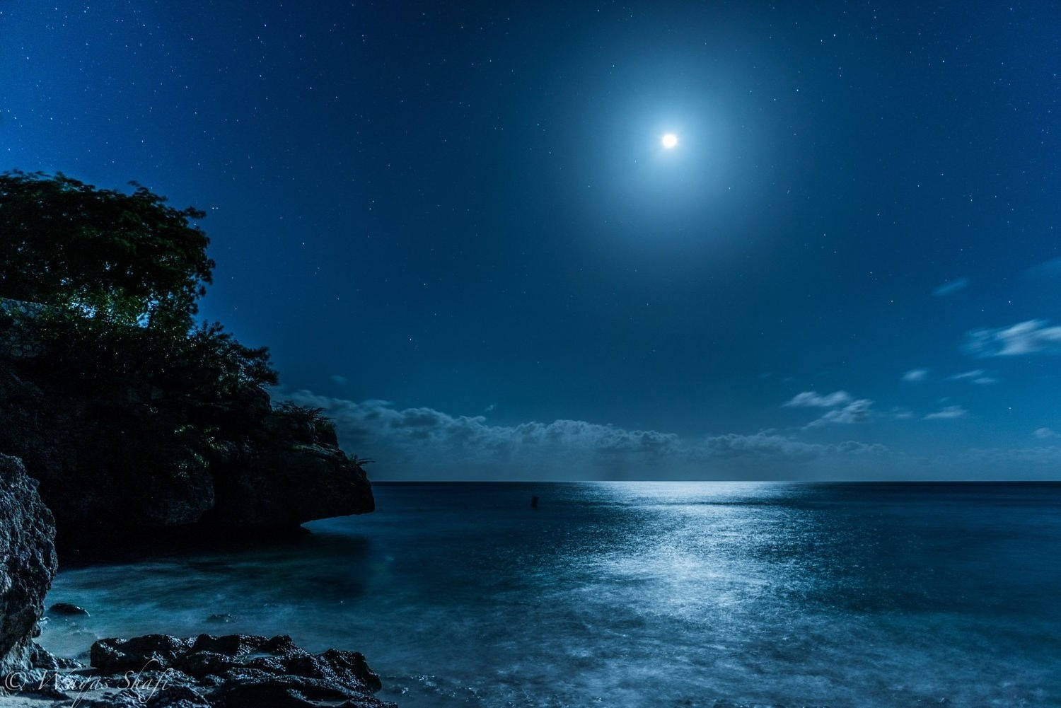 月光下的夜晚海洋，點綴著星星和岩石海岸線