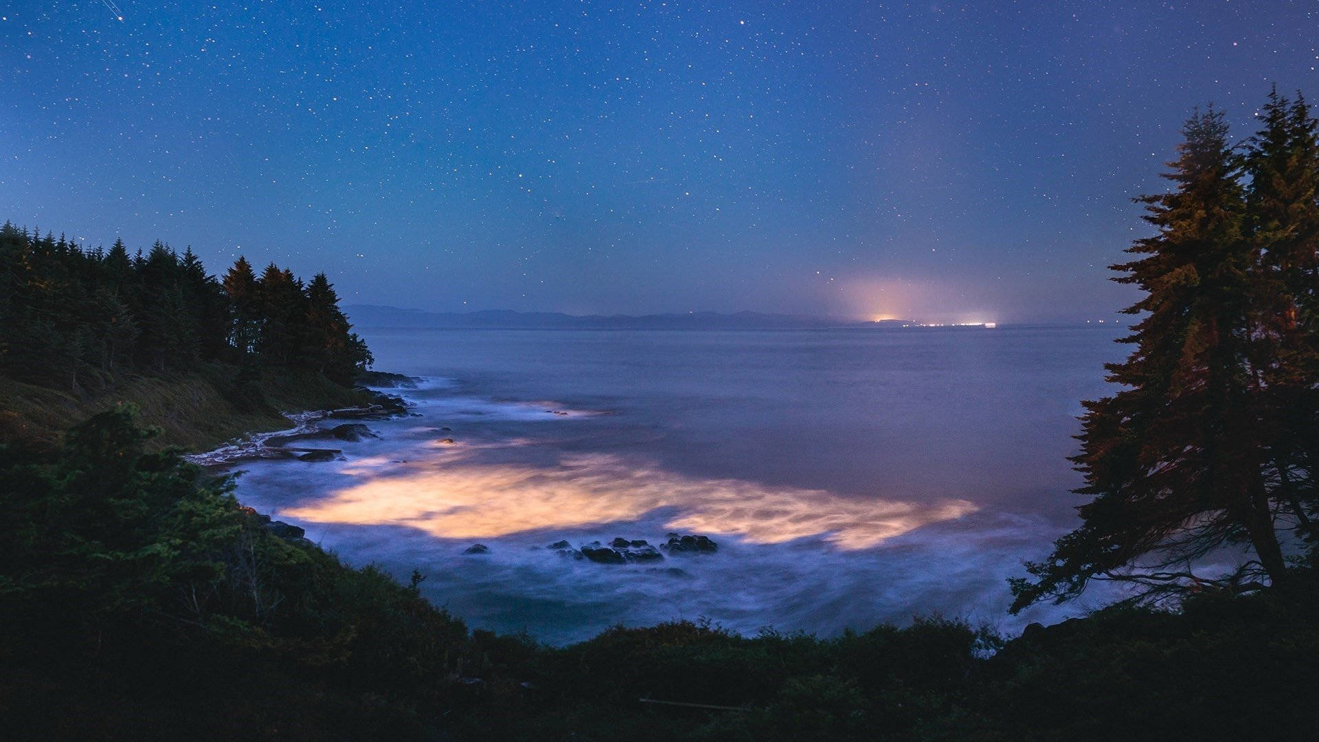 加勒比海灘夜景 壁紙 — 星光閃爍的海浪拍打岩石海岸，在深藍色夜空下，點綴著星星。