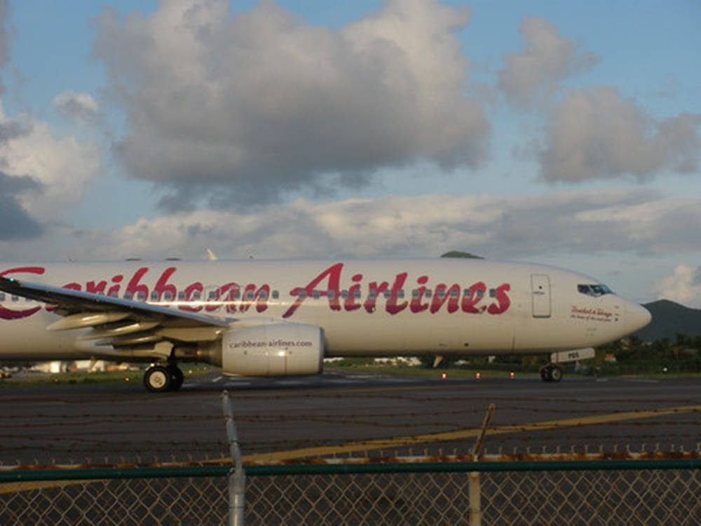 加勒比航空飛機在黃昏時分的跑道上，鐵絲網圍欄後面