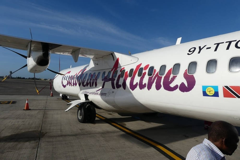 加勒比航空渦輪螺旋槳飛機在停機坪上，附近有男子