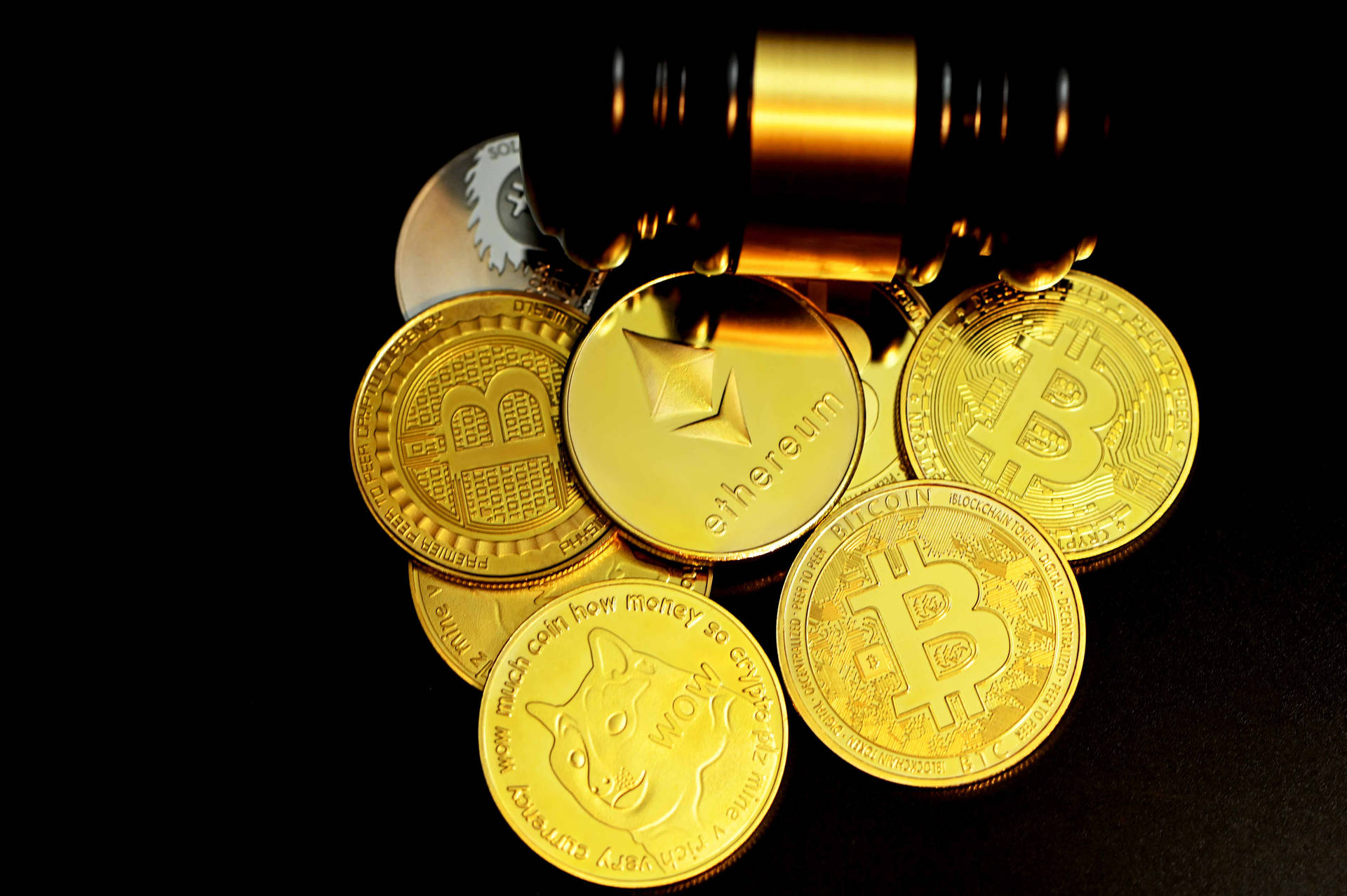 一堆金色加密貨幣硬幣，上面有槌子。