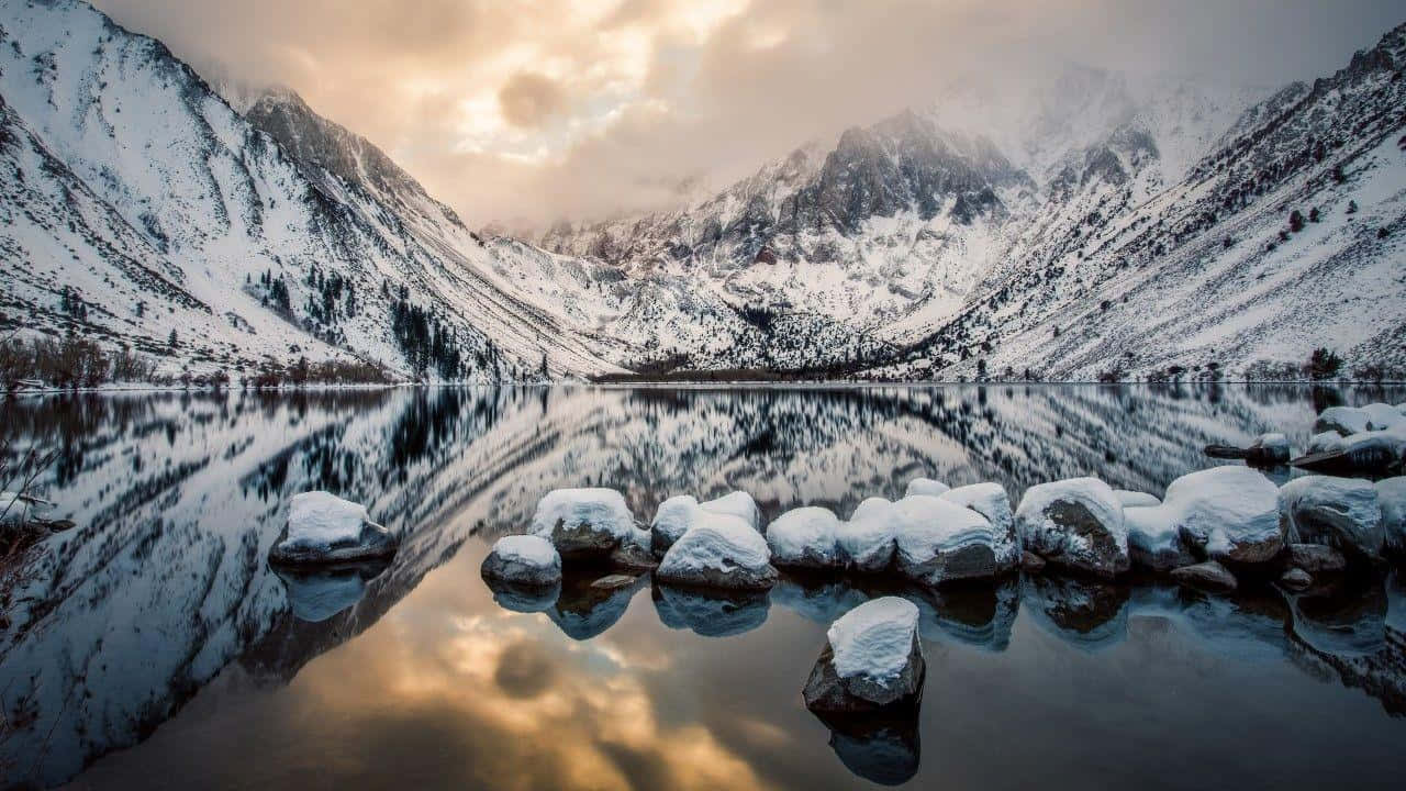 夕陽下白雪覆蓋的山脈倒映在平靜的湖面上