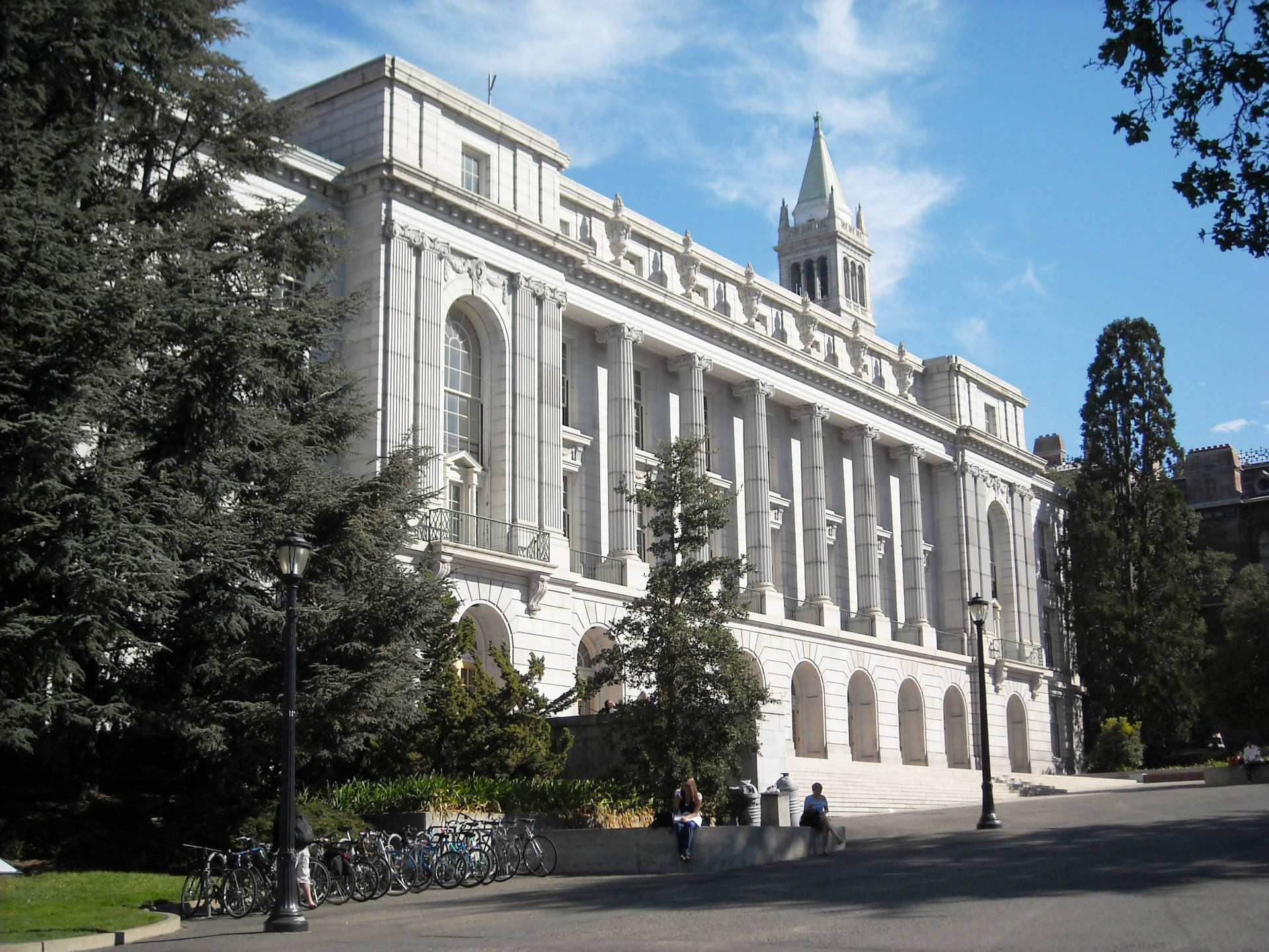 學生們在一座宏偉的大學建築附近放鬆，外面停著自行車。