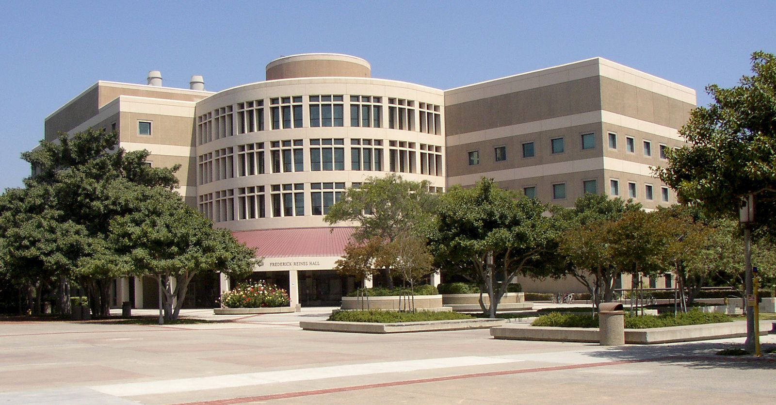 陽光明媚的日子裡，現代米色大學建築被綠樹環繞。