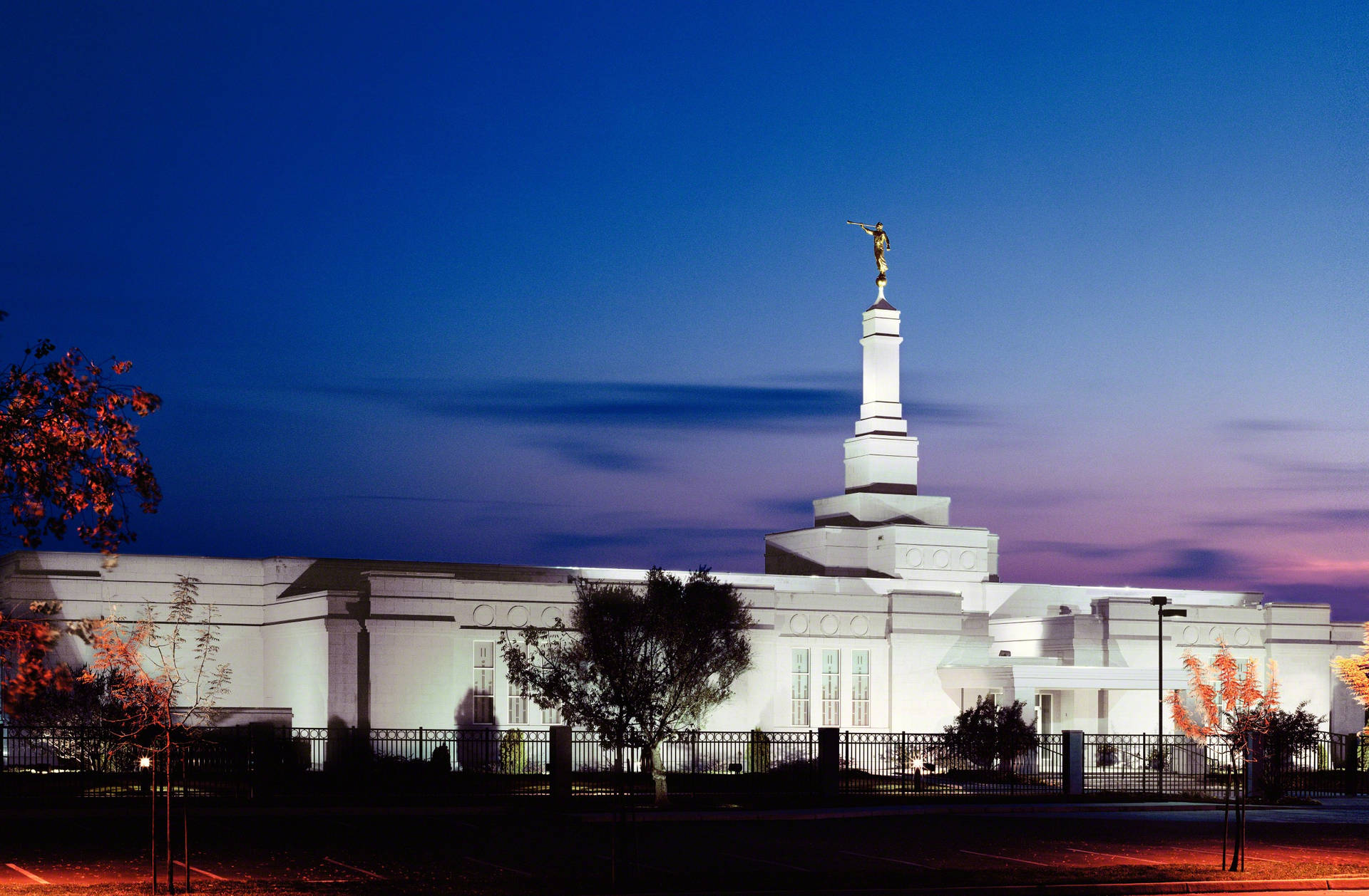 加州弗雷斯諾聖殿復古夜景 壁紙 — 一座白色寺廟在黃昏時被照亮，尖頂上有一座金色雕像，襯托著深藍和紫色的天空。