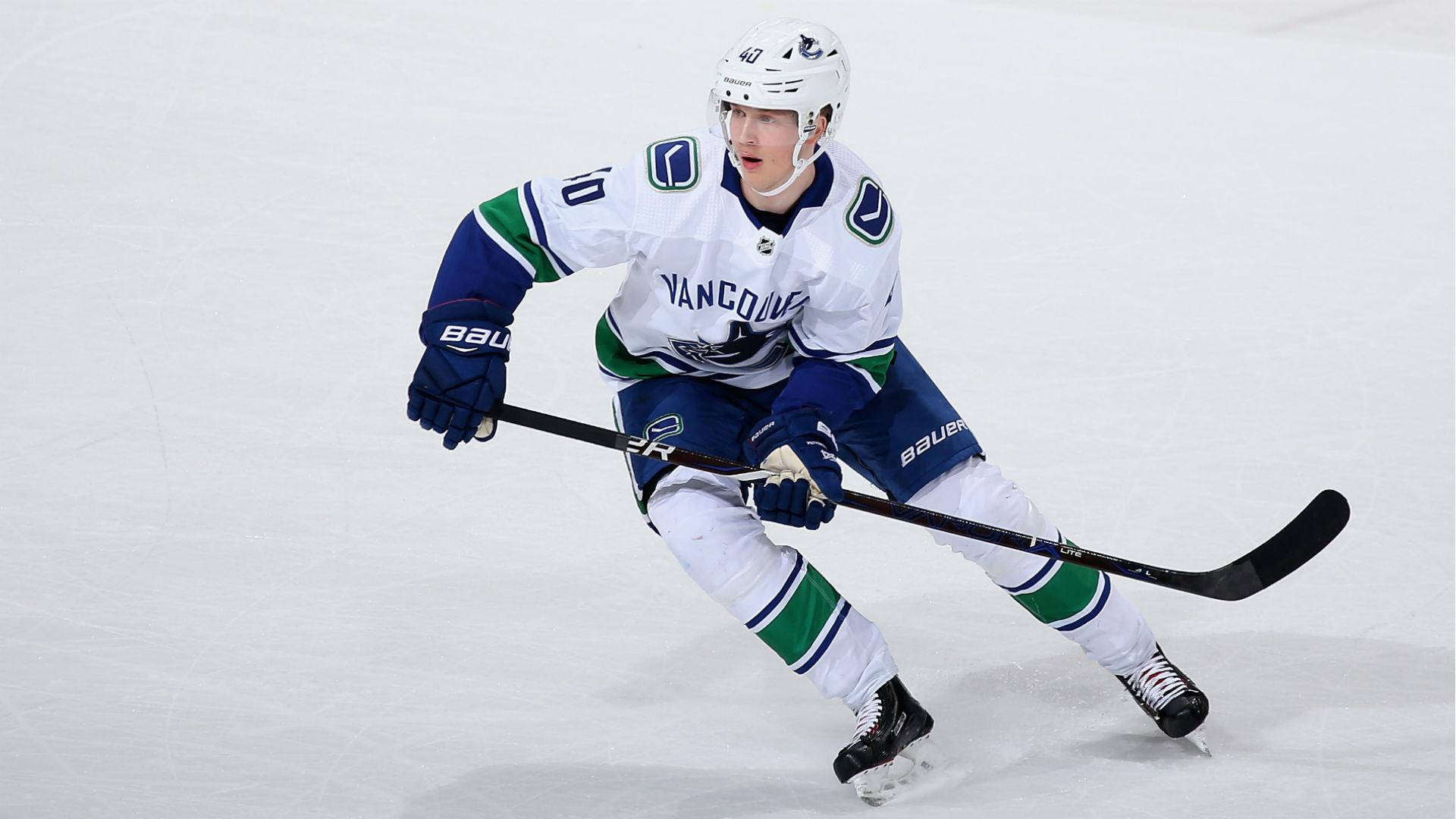 加拿大NHL球員伊萊亞斯·佩特ters森全副武裝 壁紙 — 一名溫哥華加人隊（Vancouver Canucks）冰球運動員身穿白、藍、綠色球衣，在比賽中手持球桿在冰上激烈滑行。