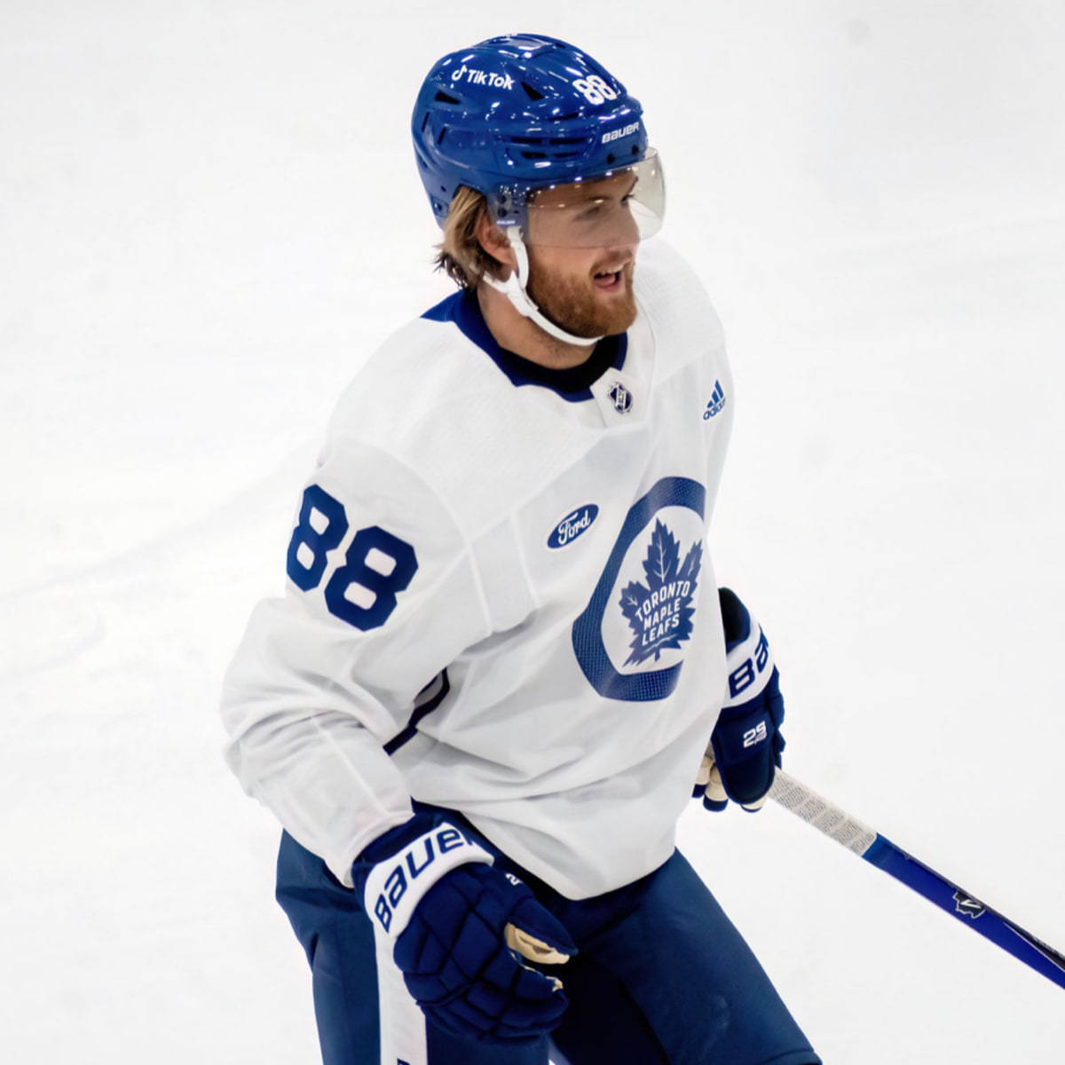 加拿大NHL球員威廉·尼蘭德2022年笑容照 壁紙 — 一名身穿多倫多楓葉隊球衣、號碼88的冰球運動員在比賽期間在冰上滑行。