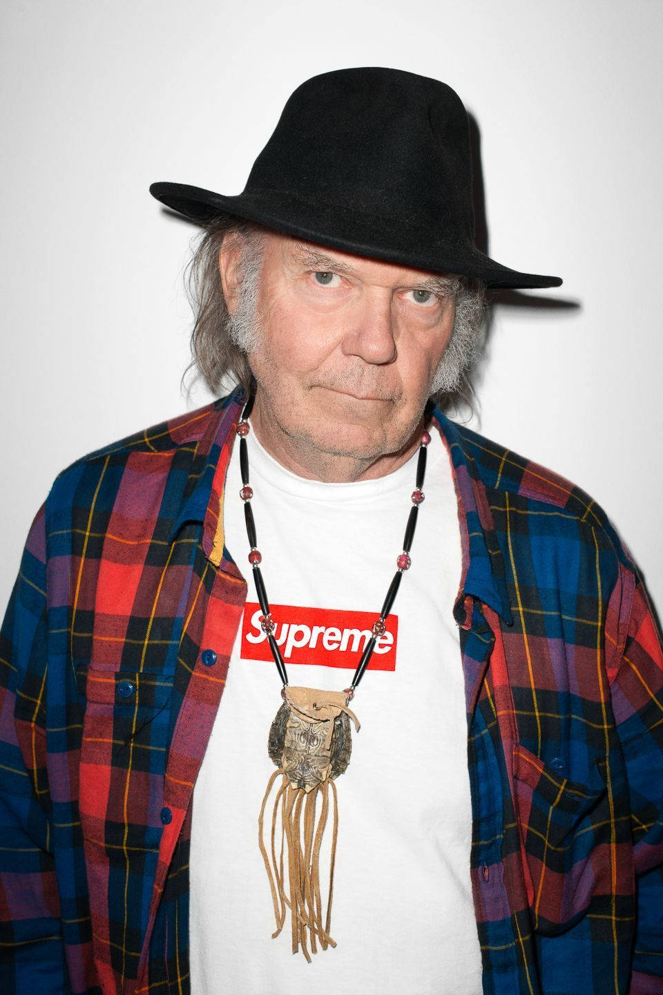 戴軟呢帽和格仔恤衫的男士穿著Supreme T恤和珠鏈。