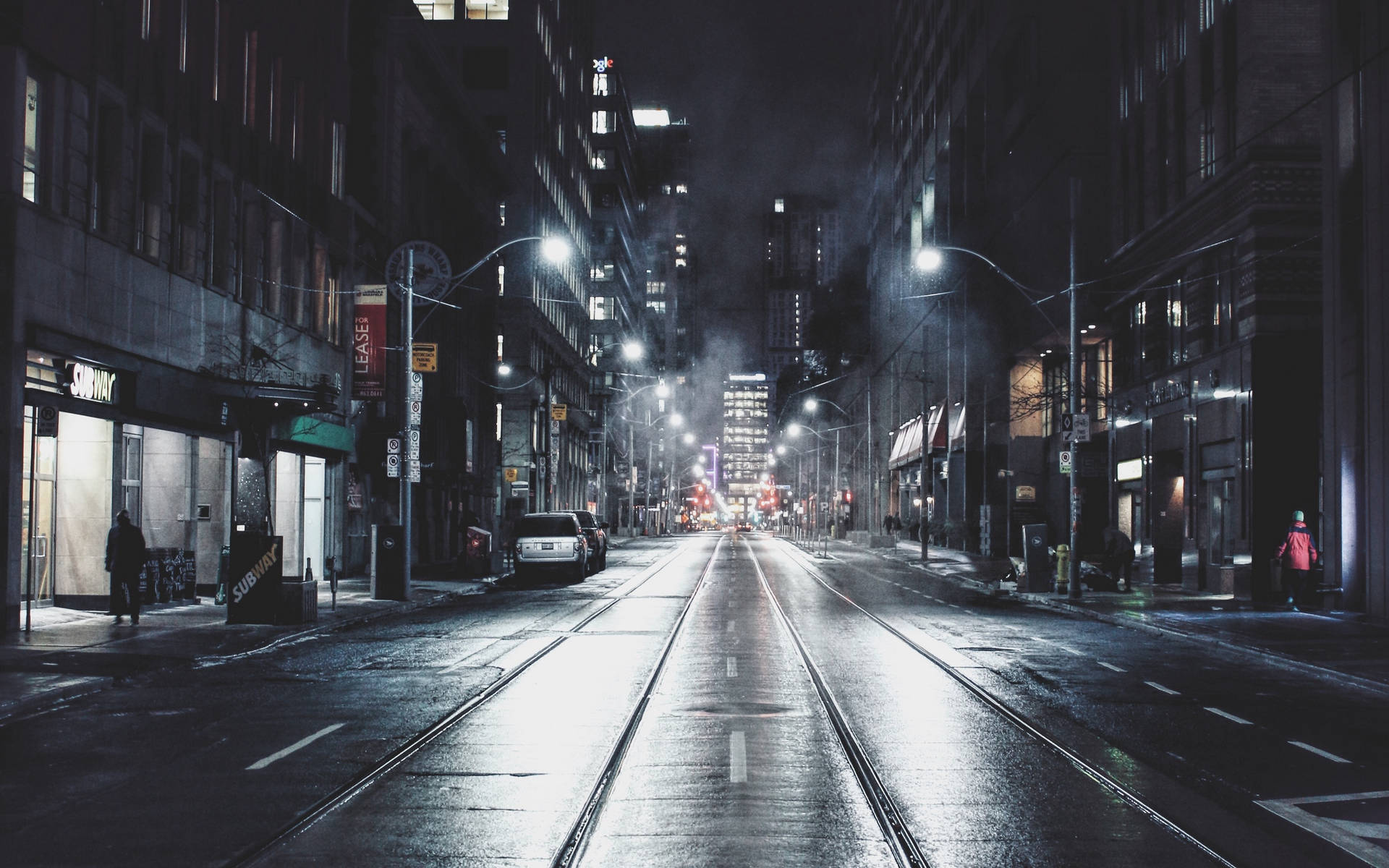 雨夜的城市街道，閃爍的路燈和遠處的車流。