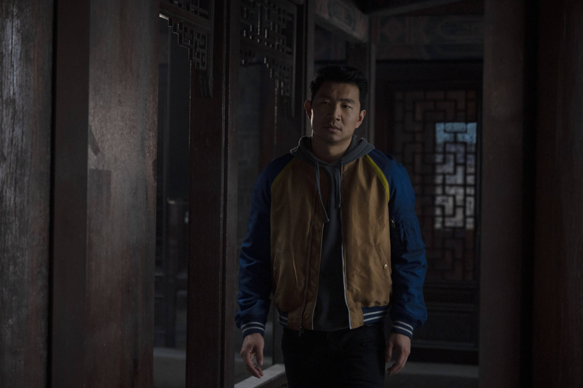 穿外套的男人站在有格子窗的傳統木製走廊中。