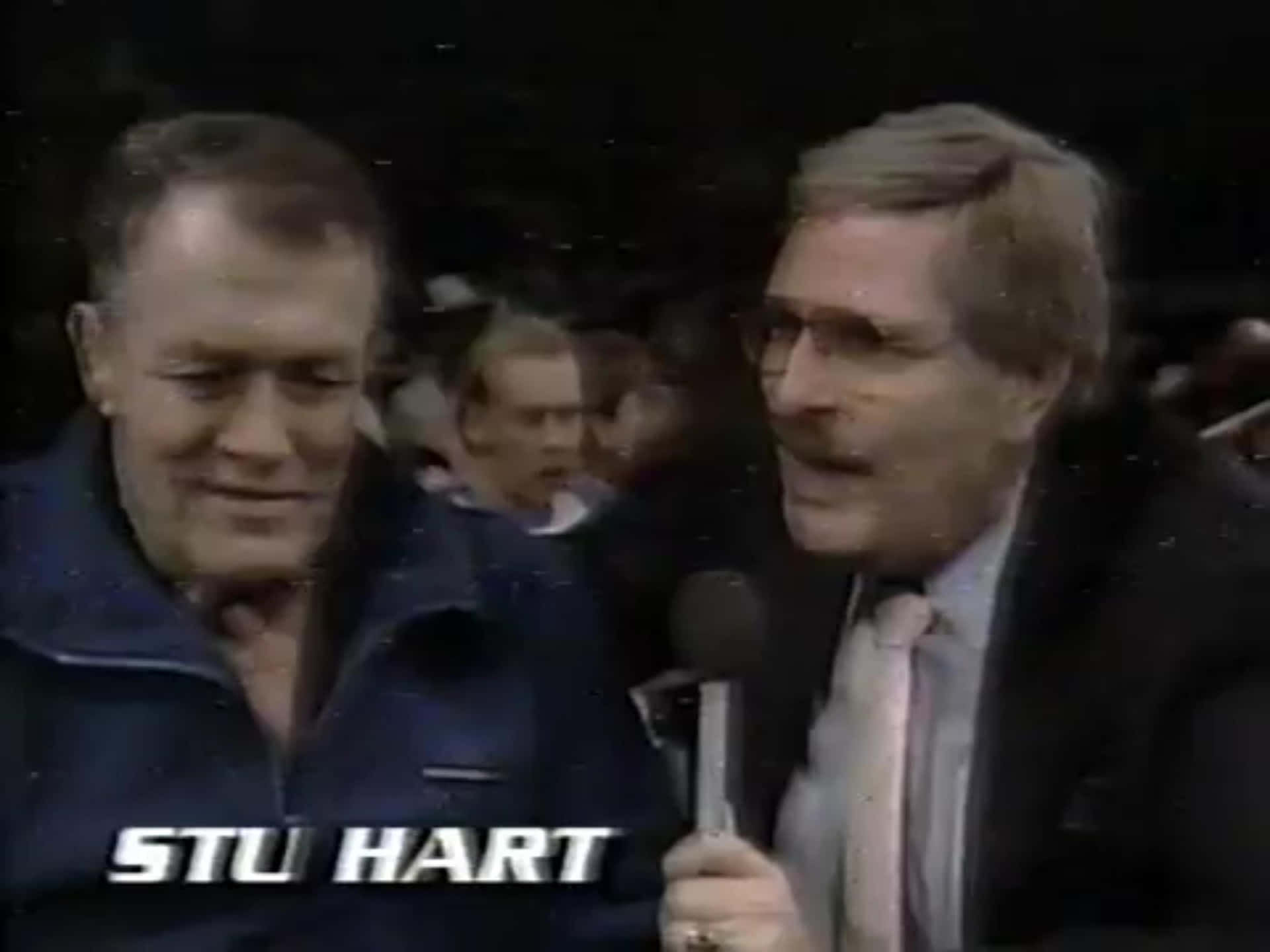 摔角手 Stu Hart 在擠滿人的競技場中接受記者訪問。