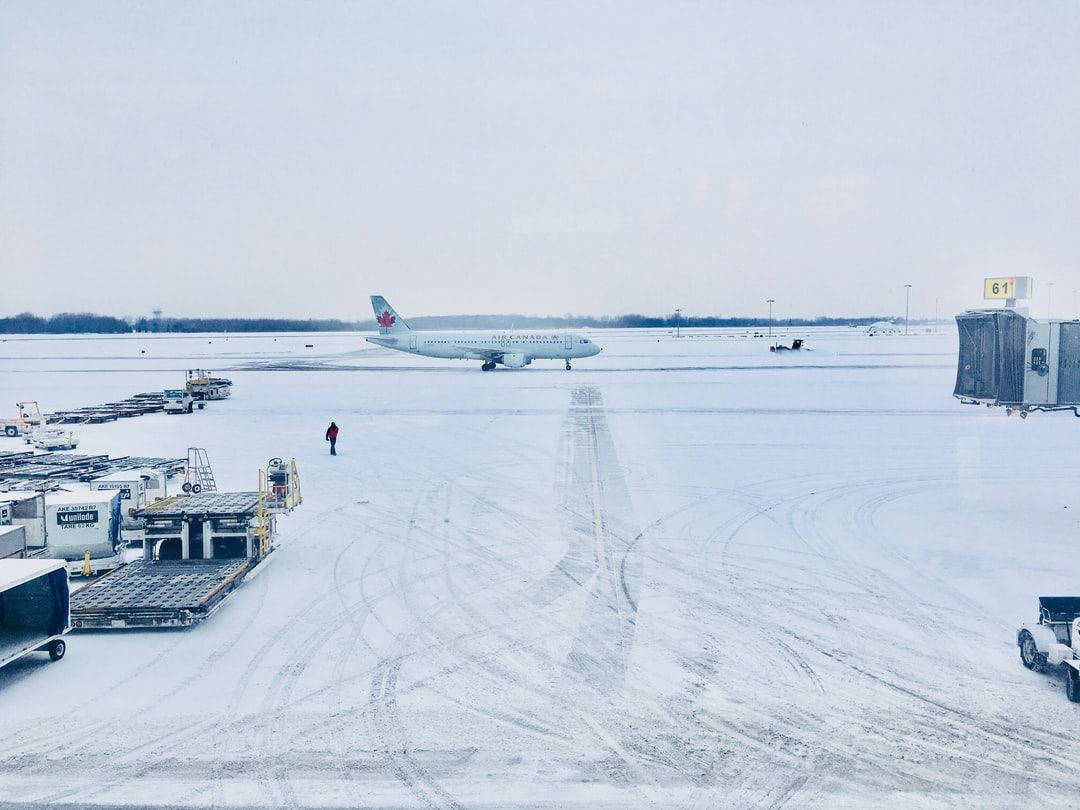 白雪覆蓋的機場停機坪，停泊著飛機和地面設備。