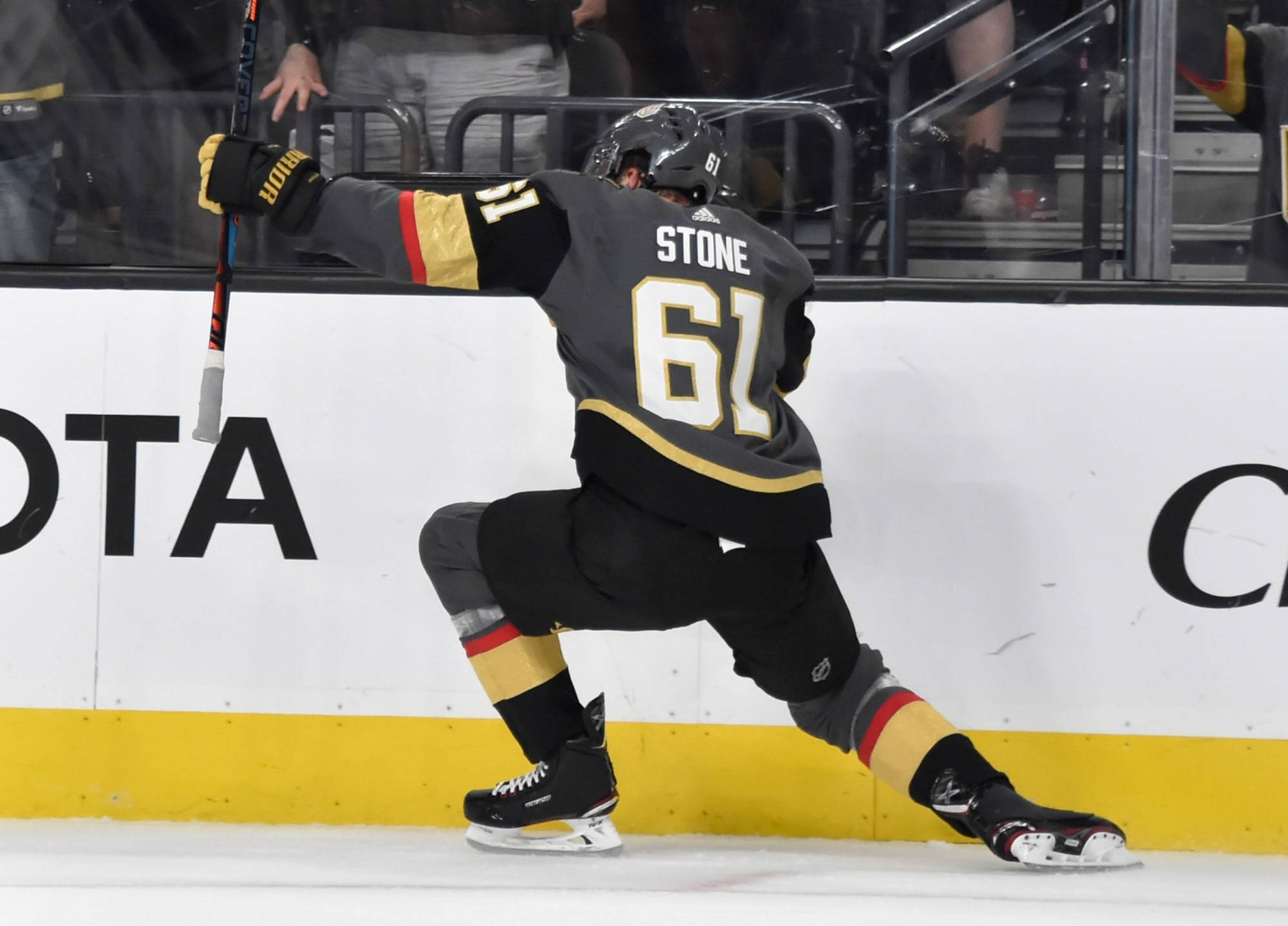 加拿大運動員馬克·斯通2019年NHL史丹利杯賽事 壁紙 — 冰球運動員Stone 61號身穿黑金色球衣在冰場上舉起球棍慶祝。