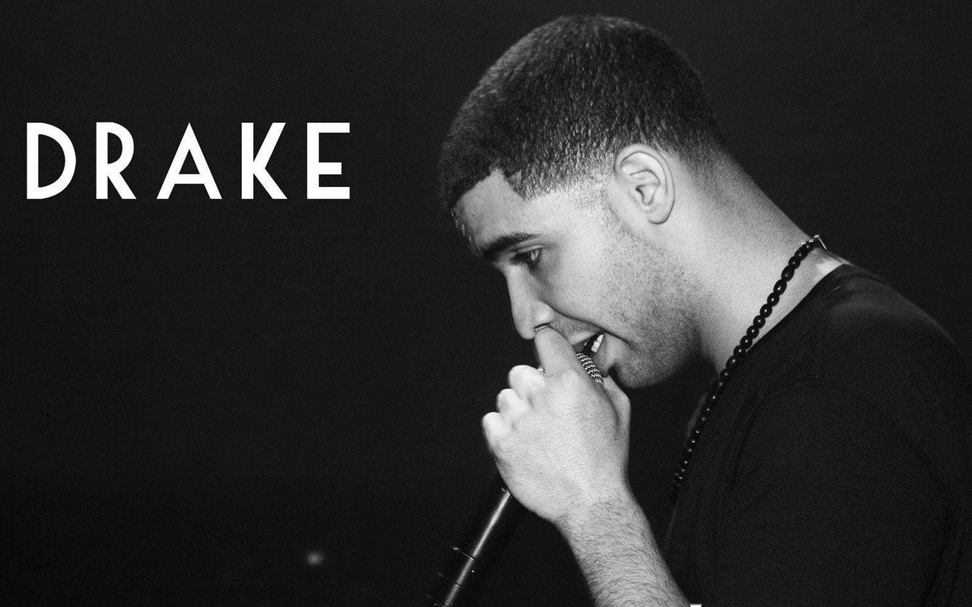 Drake 在舞台上拿著麥克風以黑白形式表演。