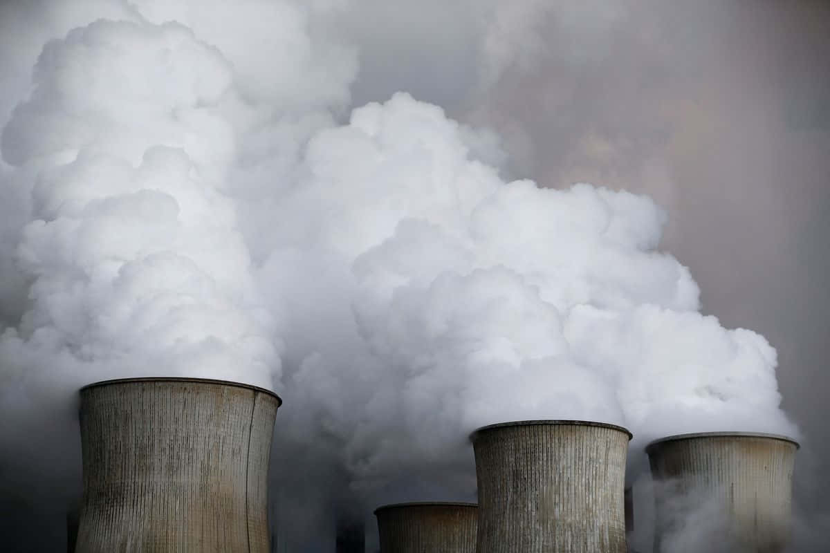 加油站的橙色加油機 壁紙 — 大量白色蒸氣從風化的工業冷卻塔中冒出，映襯著灰色的天空。