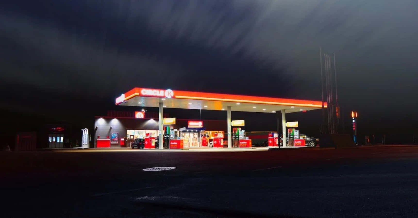 夜間照亮的Circle K加油站，一輛汽車在油泵旁。