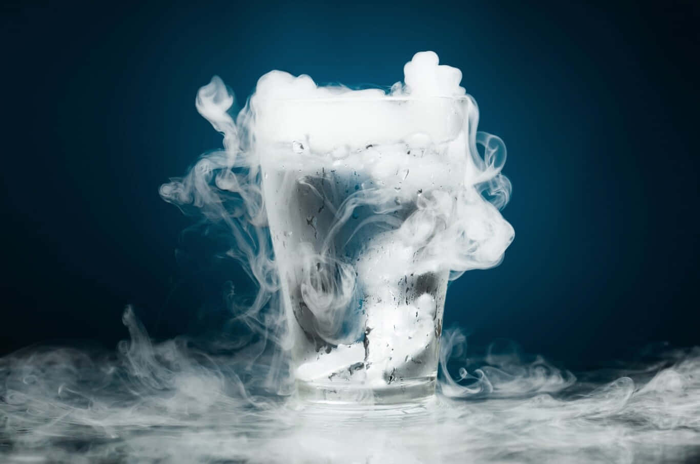 加油補給，準備啟程 壁紙 — 一個玻璃杯裝滿旋轉的白色蒸氣，在深藍色背景下營造出神秘而酷炫的氛圍。