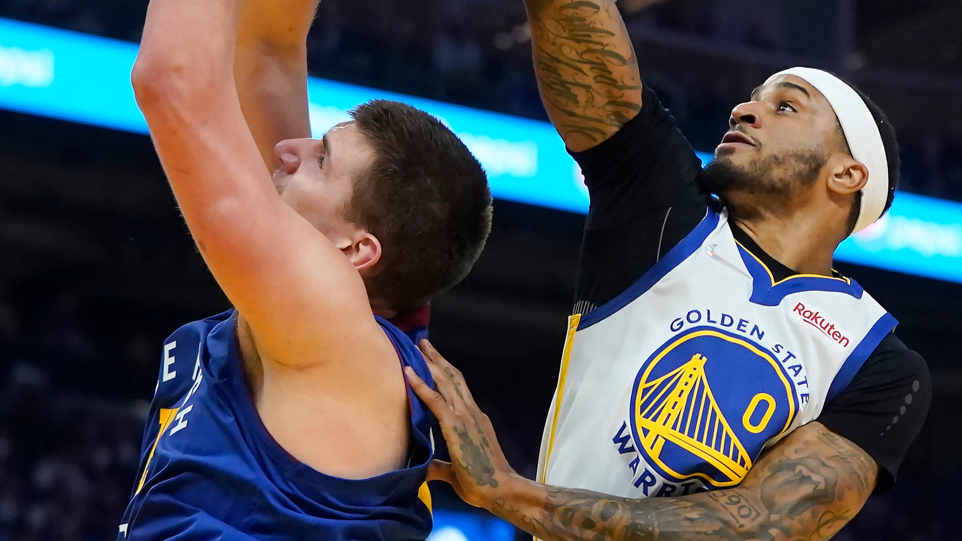 加里·佩頓效力勇士隊NBA賽事 壁紙 — 兩名籃球運動員在明亮的場館燈光下激烈爭奪投籃，身上有可見的紋身和球隊球衣。