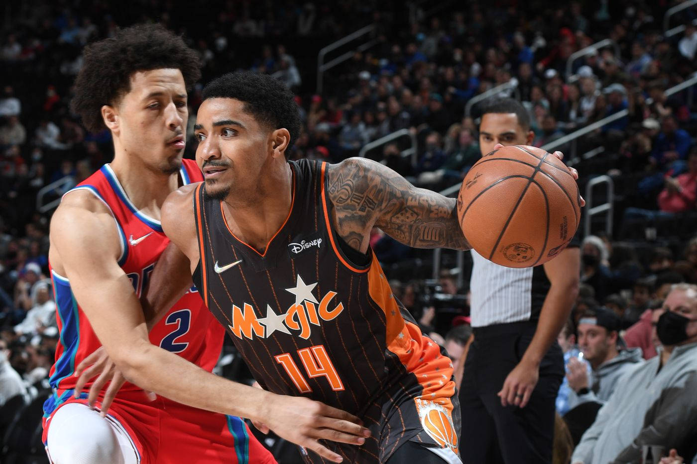 加里·哈里斯NBA聯賽 壁紙 — 一名身穿奧蘭多魔術隊球衣的籃球運動員在擠滿觀眾的場館比賽中突破防守球員。