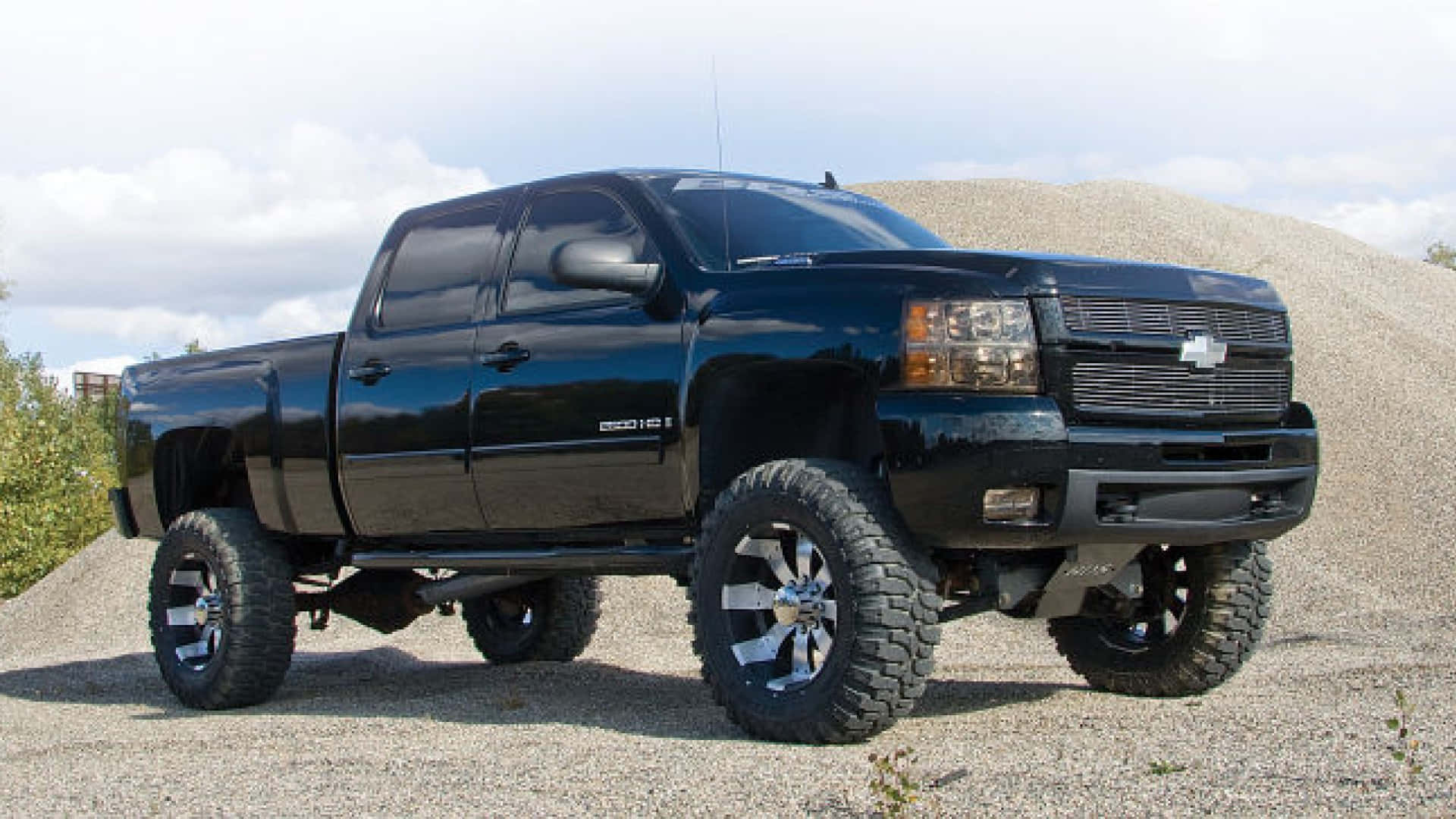 黑色升高嘅Chevrolet Silverado pickup truck停泊喺碎石堆附近嘅碎石地上。
