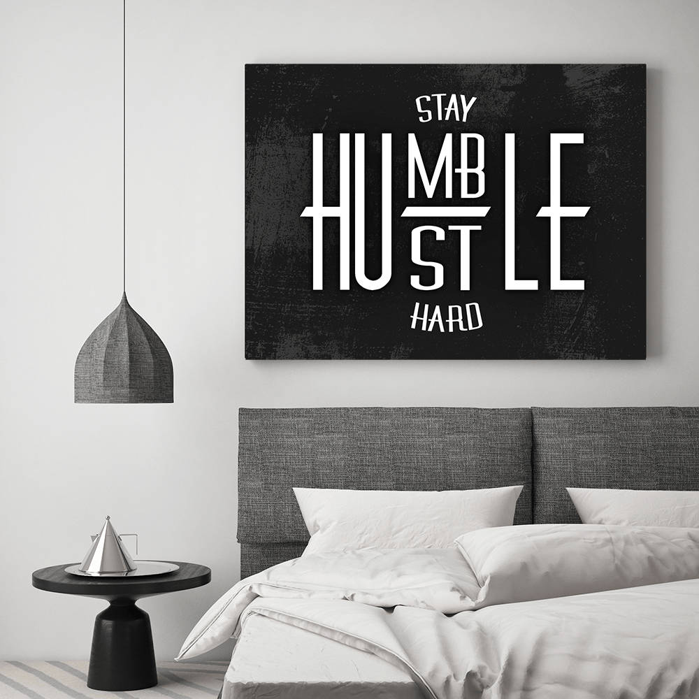 現代臥室，灰色床上方有勵志牆飾，寫著「Stay Humble Hustle Hard」。