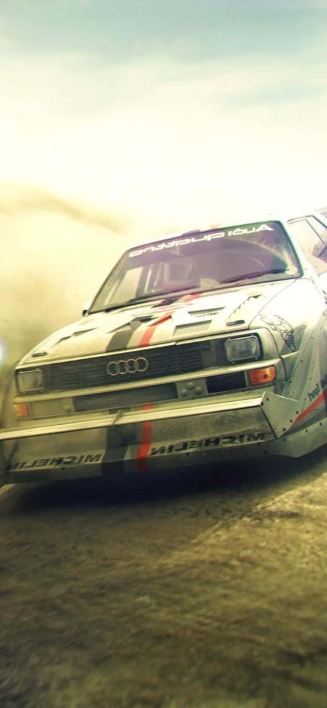 勇敢駕駛者挑戰 iPhone Xs Dirt Rally 的刺激 壁紙 — 一輛佈滿灰塵的白色奧迪拉力賽車在塵土飛揚的賽道上疾馳，在朦朧的天空下揚起陣陣塵土。