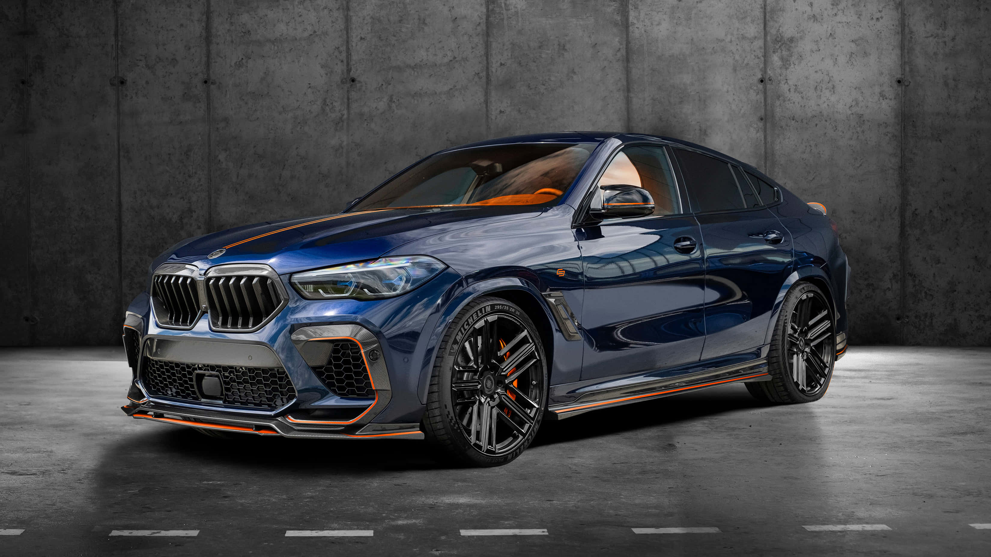 動力與性能全開 — BMW X6 M 壁紙 — 一輛時尚的藍色BMW X6 M帶有橙色點綴，在攝影棚燈光下對著紋理混凝土牆閃閃發光。