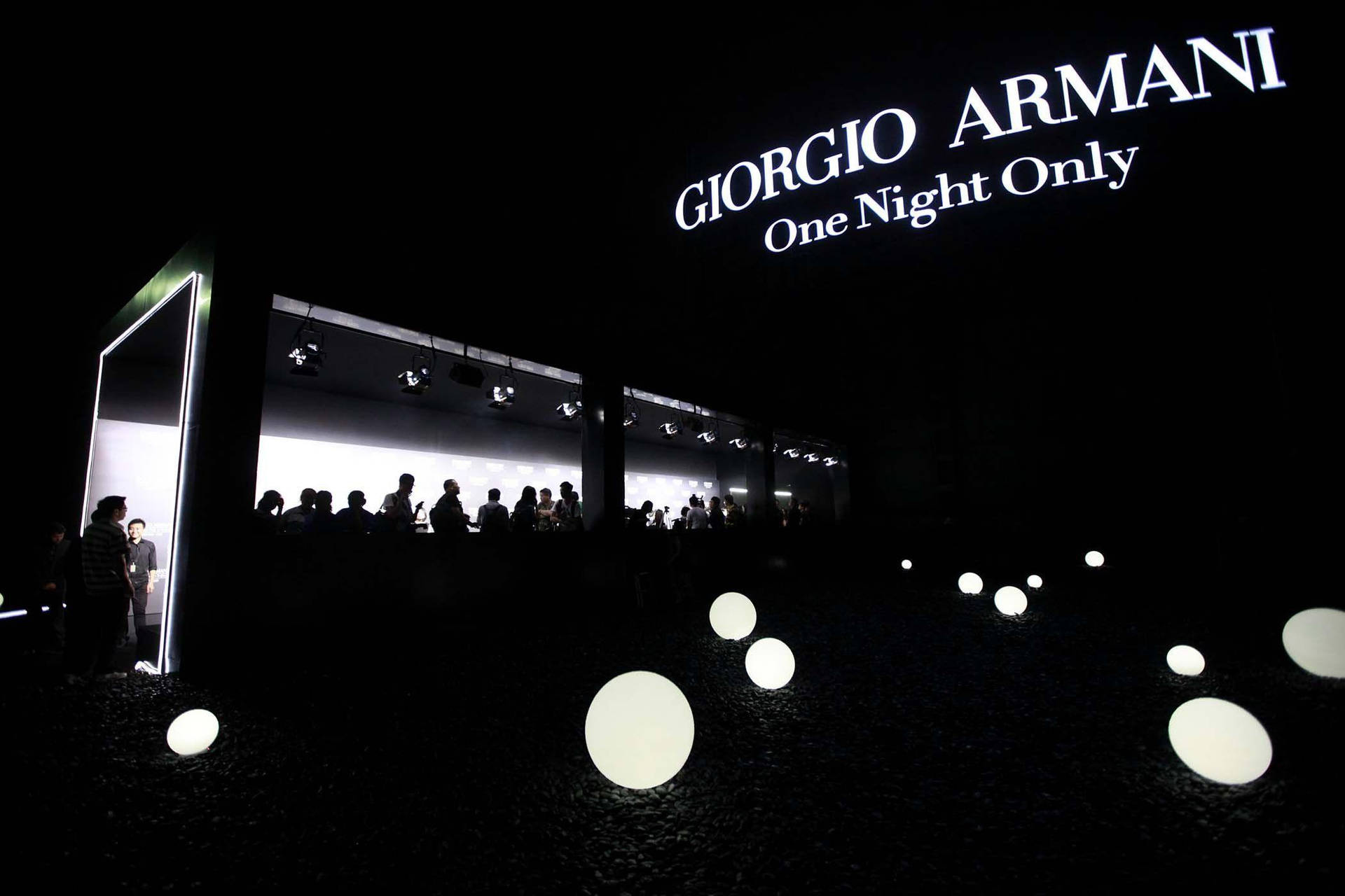 夜間活動，發光球體與Giorgio Armani標誌剪影。