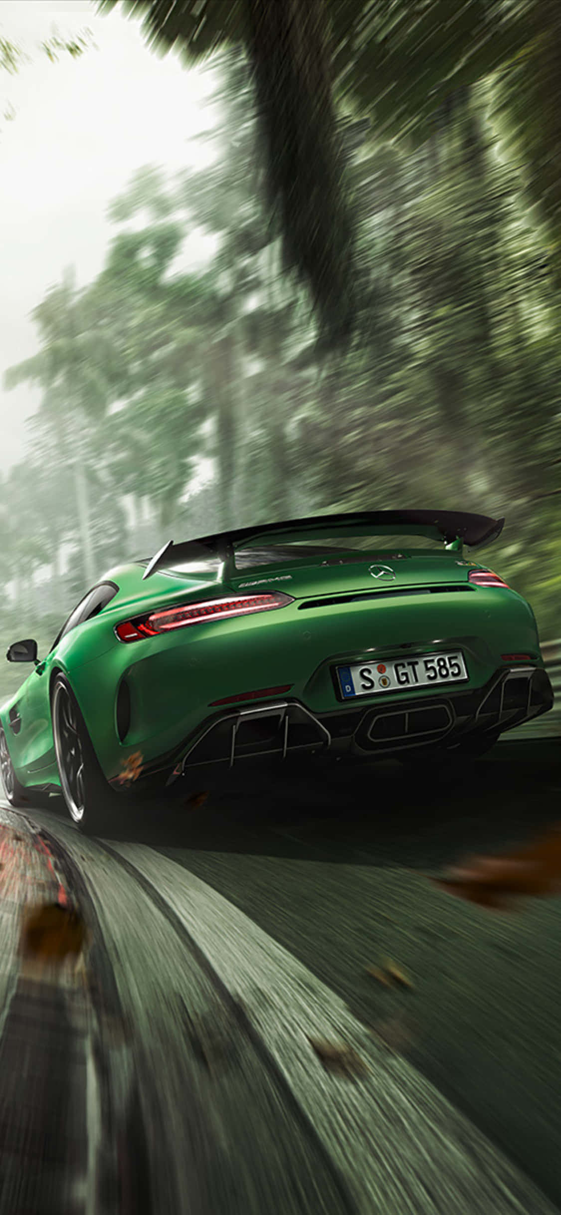 動感互動 - iPhone X 與 AMG GT-R 壁紙 — 一輛充滿活力的綠色跑車在森林道路上疾馳，帶有動態模糊和落葉效果。