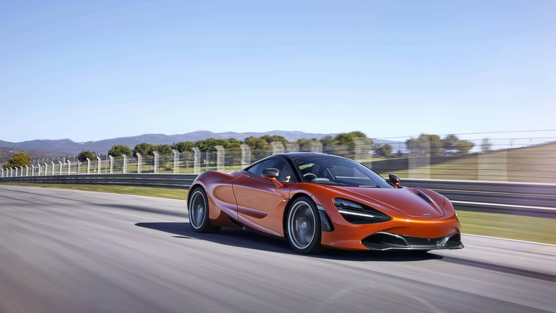 橙色McLaren 720S在賽道上疾馳，背景模糊，遠處有山脈。