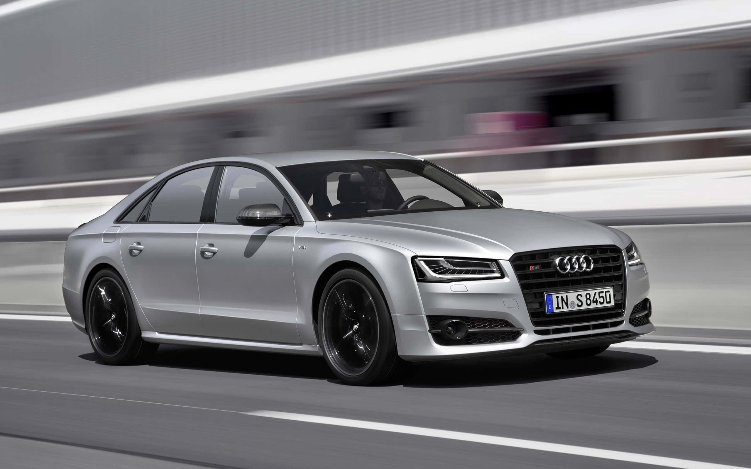 動感流線的 Audi S8 駛於公路上 壁紙 — 一架時尚的銀色奧迪S8運動轎車在現代高速公路上疾馳，背景帶有動態模糊效果。