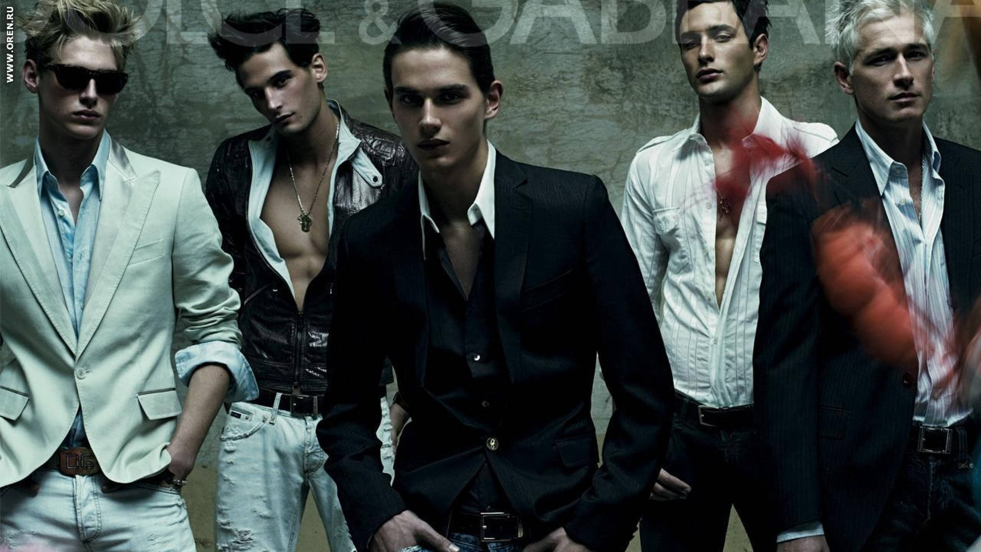 五位身穿西裝和開襟襯衫的時裝模特兒在帶有紅色潑濺的灰色牆壁前擺姿勢。